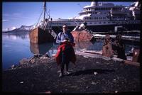 Jack Child at shore of Grytviken settlement with World Discoverer and dilapidated ships in background