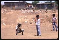 A batter and catcher wait for a pitch at a children's baseball game, Managua, Nicaragua