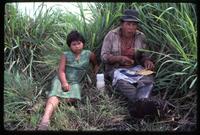 A man eats next to a young girl in the field at the state-run cooperative where they work, Sebaco, Nicaragua
