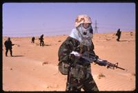 An American soldier walks through the desert wearing a gas mask during the Gulf War, Saudi Arabia