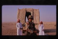 An American soldier stands between two Saudi men in the desert during the Gulf War, Saudi Arabia