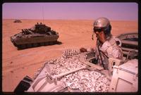 US Army tank personnel speaking on a headset with his crew while riding in a tank during the Gulf War, Saudi Arabia