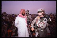 A female soldier stands near a Saudi man wearing a shemagh during the Gulf War, Dhahran, Saudi Arabia