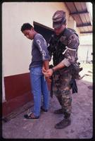 An American Military Police wearing the US Army banana boat patch securing a prisoner during the United States Invasion of Panama, Arraijan, Panama