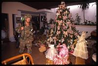 An American soldier with the 82nd Airborne Division walks past a decorated Christmas tree, probably Manuel Noriega's home, during the United States Invasion of Panama, Panama 