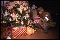 An American soldier with the 82nd Airborne Division inspects the gifts under a Christmas tree in a home, probably Manuel Noriega's, during the United States Invasion of Panama, Panama City, Panama