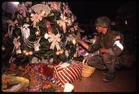 An American soldier with the 82nd Airborne Division inspecting an ornament on a Christmas tree, probably in Manuel Noriega's home, during the United States Invasion of Panama, Panama
