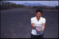 A man holds a handful of ash covering buried plants after the eruption of the Cerro Negro volcano