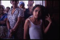 A young girl leans in a doorway with community members standing behind her after the eruption of the Cerro Negro volcano