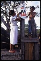 A woman and child hang a poster for the Sandinista National Liberation Front campaign, Matagalpa, Nicaragua