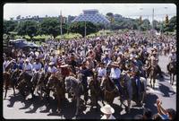 People riding on horseback lead a group of Sandinista supporters down the street at a National Union of Farmers and Ranchers Rally, Managua, Nicaragua