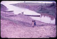 View of native children near river with boats in background