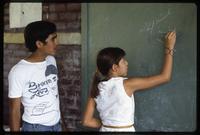 A Cuban math teacher helps a student with an exercise at a public school, Nicaragua
