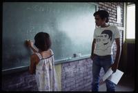 A Cuban math teacher watches a student complete a problem on the blackboard, Nicaragua