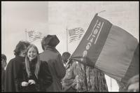 A young woman smiles near a man carrying a Mongolian flag at an anti-war rally at the Sylvan Theater, 26 October 1968