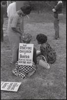 A group of women in the process of pinning signs to one another participate in a Biafra rally at the Sylvan Theater, 12 October 1968