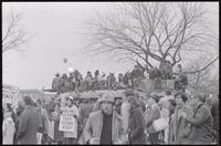 Alternate view of students on top of a painted bus, gathered to protest Nixon's inauguration and the Vietnam War, 19 January 1969