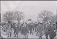 Figures in front of a protest march led by GIs and veterans preparing to set out from 15th St SW and Independence Ave SW. Protesters gathered to demonstrate against Nixon's inauguration and the Vietnam War, 19 January 1969