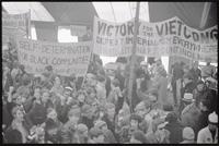Protesters hold up signs ("Self-determination for black communities; Youth Against War & Fascism", "Victory for the Viet Cong") under the counter-inaugural tent during a rally against Nixon's inauguration and the Vietnam War, 19 January 1969
