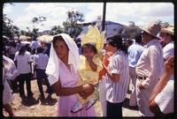 A toddler is carried by a woman through the streets while attending a Good Friday procession , Managua, Nicaragua