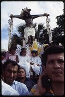 Children wearing angel costumes sit at the base of a crucifix during a religious procession, Managua, Nicaragua