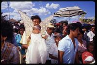 Participants in a Good Friday procession, including a man carrying a baby dressed as an angel, Managua, Nicaragua