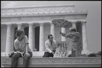 A woman observes a duo of figures representing Nixon and Kissinger as they point to a sign ("Pull out, Dick") in front of the Lincoln Memorial at a masquerade during the Vietnam Veterans Against the War demonstration, 04 July 1974