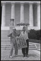 Figures dressed as Richard Nixon and Henry Kissinger gesture to passersby from the steps of the Lincoln Memorial, holding a sign ("Pull out, Dick") at a masquerade during the Vietnam Veterans Against the War demonstration, 04 July 1974
