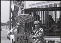 A figure of Kissinger mimes bashfulness as a figure of Nixon points to his sign ("Pull out, Dick") in front of the Lincoln Memorial at a masquerade during the Vietnam Veterans Against the War demonstration, 04 July 1974