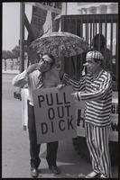 A figure of Kissinger miming bashfulness or scandal as a figure of Nixon points to his sign ("Pull out, Dick") in front of the Lincoln Memorial at a masquerade during the Vietnam Veterans Against the War demonstration, 04 July 1974