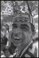 Close-up of a man in a Nixon mask at a masquerade during the Vietnam Veterans Against the War demonstration, 04 July 1974