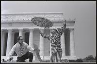 A kneeling figure of Nixon mimes supplication or being absolved next to a figure of Kissinger in front of the Lincoln Memorial at a masquerade during the Vietnam Veterans Against the War demonstration, 04 July 1974