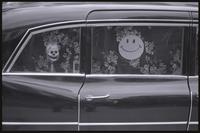 A car window is decorated with a hanging skull and a smiley face in front of a flower printed sheet, in the midst of an organized protest against Richard Nixon's second inauguration, 20 January 1973