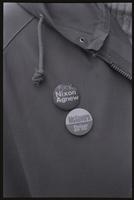A close-up of two political buttons ("Fuck Nixon, Agnew," "McGovern, Shriver") pinned to a windbreaker, taken at an anti-Nixon inauguration rally, 20 January 1973