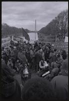 Demonstrators against Richard Nixon's second inauguration gathering around a trash can fire in front of the Reflecting Pool while holding various signs and banners, 20 January 1973