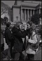 Women paint and draw on fellow protesters' faces on Constitution Ave near the National Archives during anti-war demonstrations, possibly Vietnam War Out Now, 17-24 April 1971