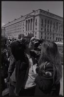Women paint and draw on fellow protesters' faces on Constitution Ave near the Department of Justice during anti-war demonstrations, possibly Vietnam War Out Now, 17-24 April 1971
