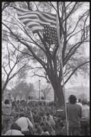 An American flag flies upside down near protesters seated for a rally on the National Mall during anti-war demonstrations, possibly Vietnam War Out Now, 17-24 April 1971