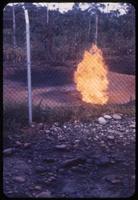 View of gas burn-off behind fence
