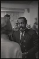 Charles Cassell smokes a pipe and speaks to an audience member during a meeting at Concordia Church, Washington, D.C., 14 February 1968 or 1969