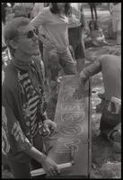A sunglasses-wearing man kneels next to a coffin with "Freedom" on it at a protest against the police brutality at the Democratic National Convention in Chicago, Lafayette Park, 31 August 1968