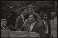 Former U.S. Representative Adam Clayton Powell sits as people converse behind him at American University, 13 October 1968