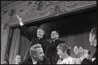 Two dissenting priests, who oppose Cardinal O'Boyle's support of the Humanae Vitae, acknowledge applause while standing behind Senator Eugene McCarthy at the Unity Day Rally hosted in the Mayflower Hotel, Washington, D.C., 10 November 1968