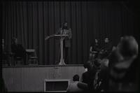 Dick Gregory stands on stage and speaks to a crowd of students at American University, Washington, D.C., 16 February 1969