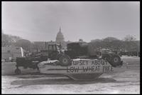 An upside-down car, on which is written "Upset about low wheat price," sits on the National Mall near the U.S. Capitol Building during the American Agriculture Movement's second Tractorcade demonstration in Washington, D.C., 28 February 1979