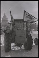 A tractor parked on the National Mall and displaying an American Agriculture Movement flag and signs that read "Help save American farms from foreign investors" and "Hay for jack asses in Washington D.C." during the American Agriculture Movement's second 