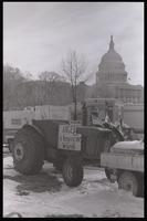 Vehicles and a tractor bearing a sign that says "Anger is keeping me warm" are parked along the National Mall near the U.S. Capitol Building during the American Agriculture Movement's second Tractorcade demonstration in Washington, D.C., 28 February 1979