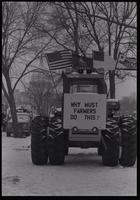 A tractor displays a protest sign reading "Why must farmers do this?" while sitting parked on the National Mall near the U.S. Capitol Building during the American Agriculture Movement's second Tractorcade demonstration in Washington, D.C., 28 February 197