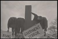 Actors participating in the mock crucifixion hang over the cross and hold signs during the Vietnam Passion Play outside the White House, organized by the Committee for a Sane Nuclear Policy, Washington, D.C., 06 April 1969