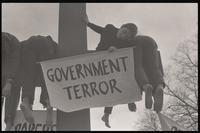 An actor participating in the mock crucifixion hangs over the cross and holds a sign that says "Government terror" during the Vietnam Passion Play outside the White House, organized by the Committee for a Sane Nuclear Policy, Washington, D.C., 06 April 19